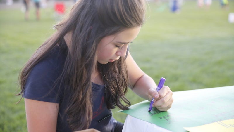Maya McGee, of Farmington, writers down her pledge to fight cancer during Saturday's Relay for Life at the Boys & Girls Clubs of Farmington football field.