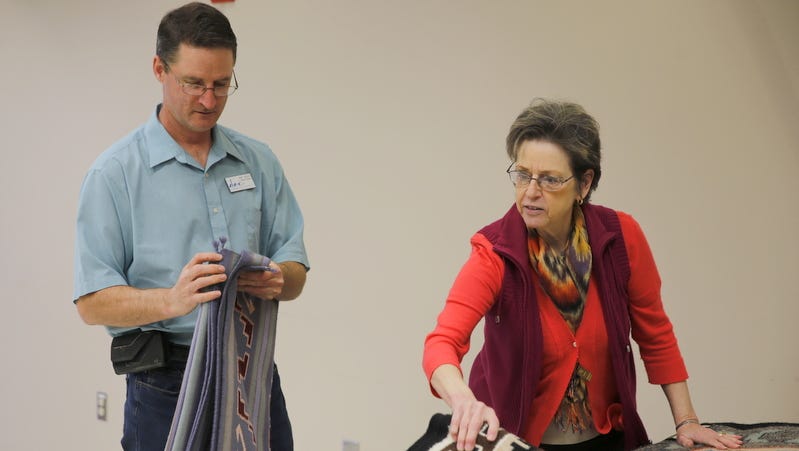 Director Bart Wilsey and Executive Administrative Assistant Penny Jew-Garcia examine some of the pieces that will be featured in this weekend's Navajo rug auction on Wednesday at the Farmington Museum at Gateway Park.