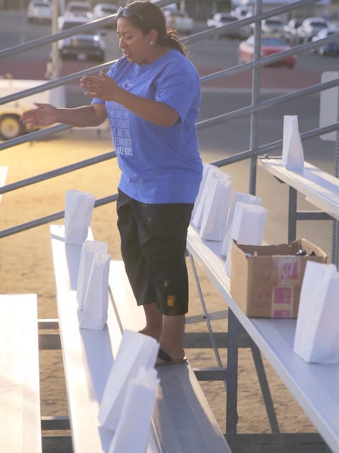 Event leader Mychelle McGee lights luminarias in the stands during Saturday's Relay for Life at the Boys & Girls Clubs of Farmington football field.