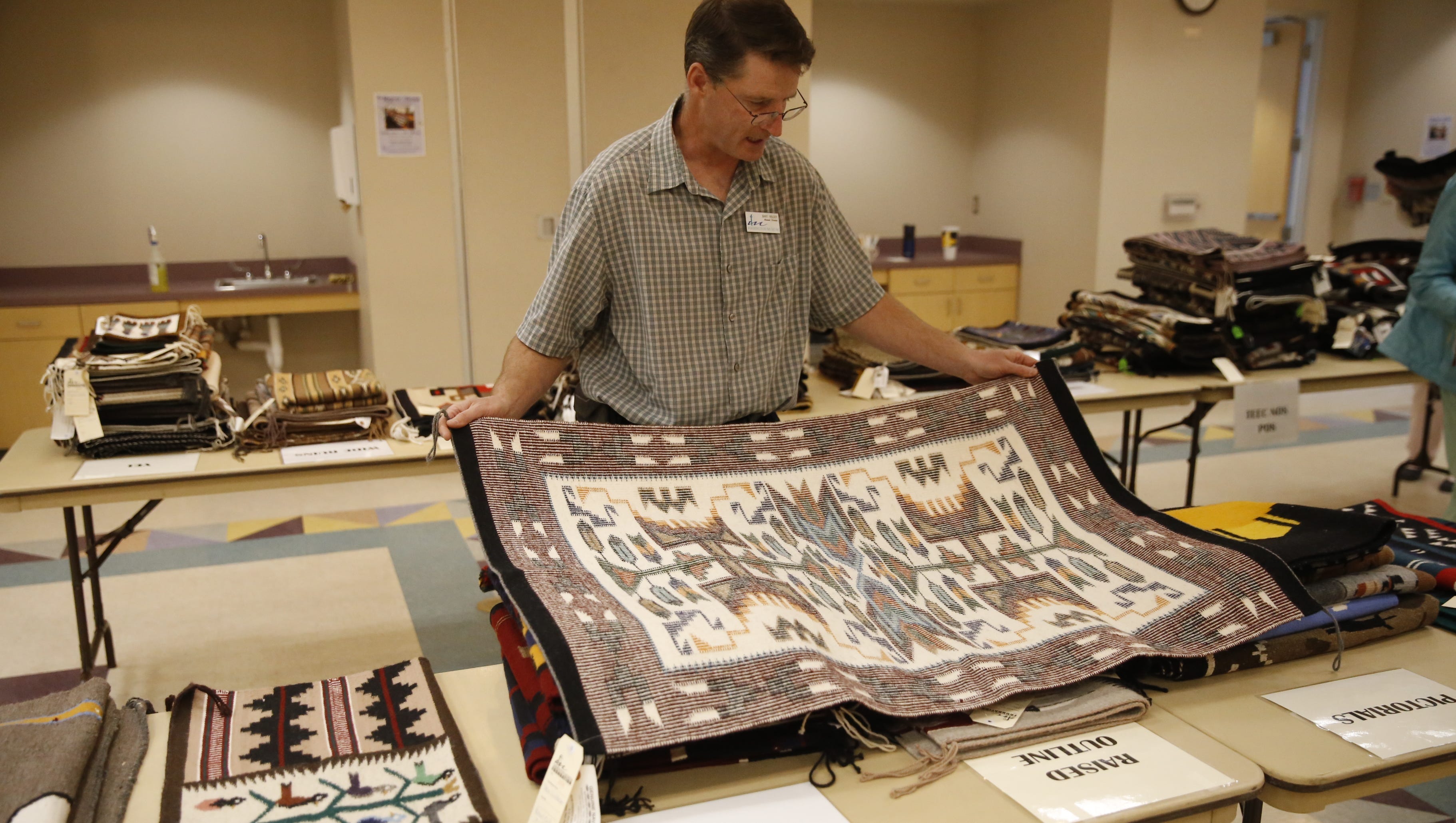Farmington Museum director Bart Wilsey displays a raised outline weaving that will be featured during Saturday's annual Navajo Rug Benefit Auction at the museum.
