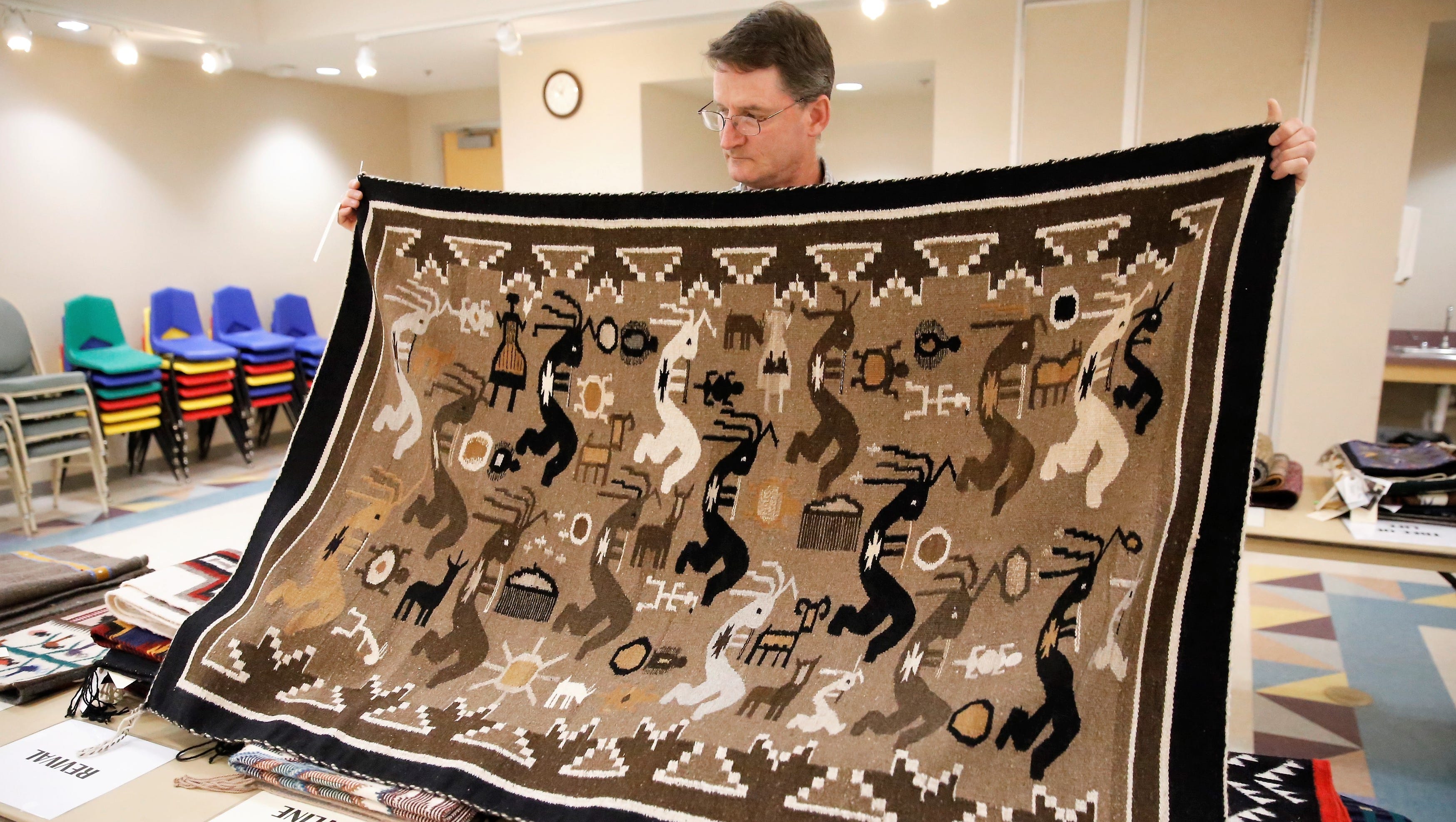 Farmington Museum director Bart Wilsey holds a Kokopelli rug by Esther Etcitty that will be included in Saturday's Navajo Rug Benefit Auction at the museum.