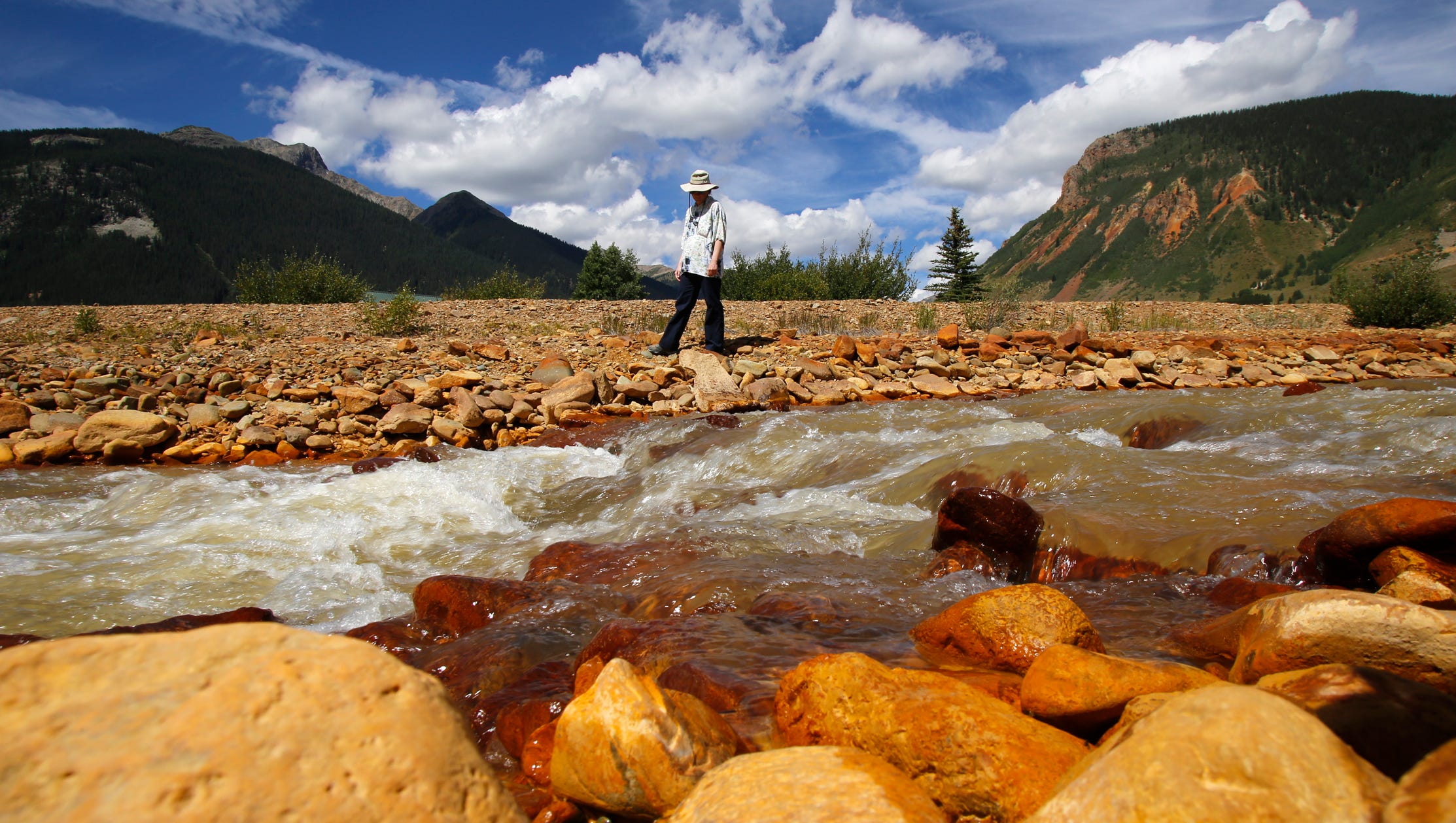 Melanie Bergolc, a resident of Silverton, Colo., walks along the banks of Cement Creek in Silverton on Aug. 10, 2015, where residue from the Gold King Mine spill is evident.
