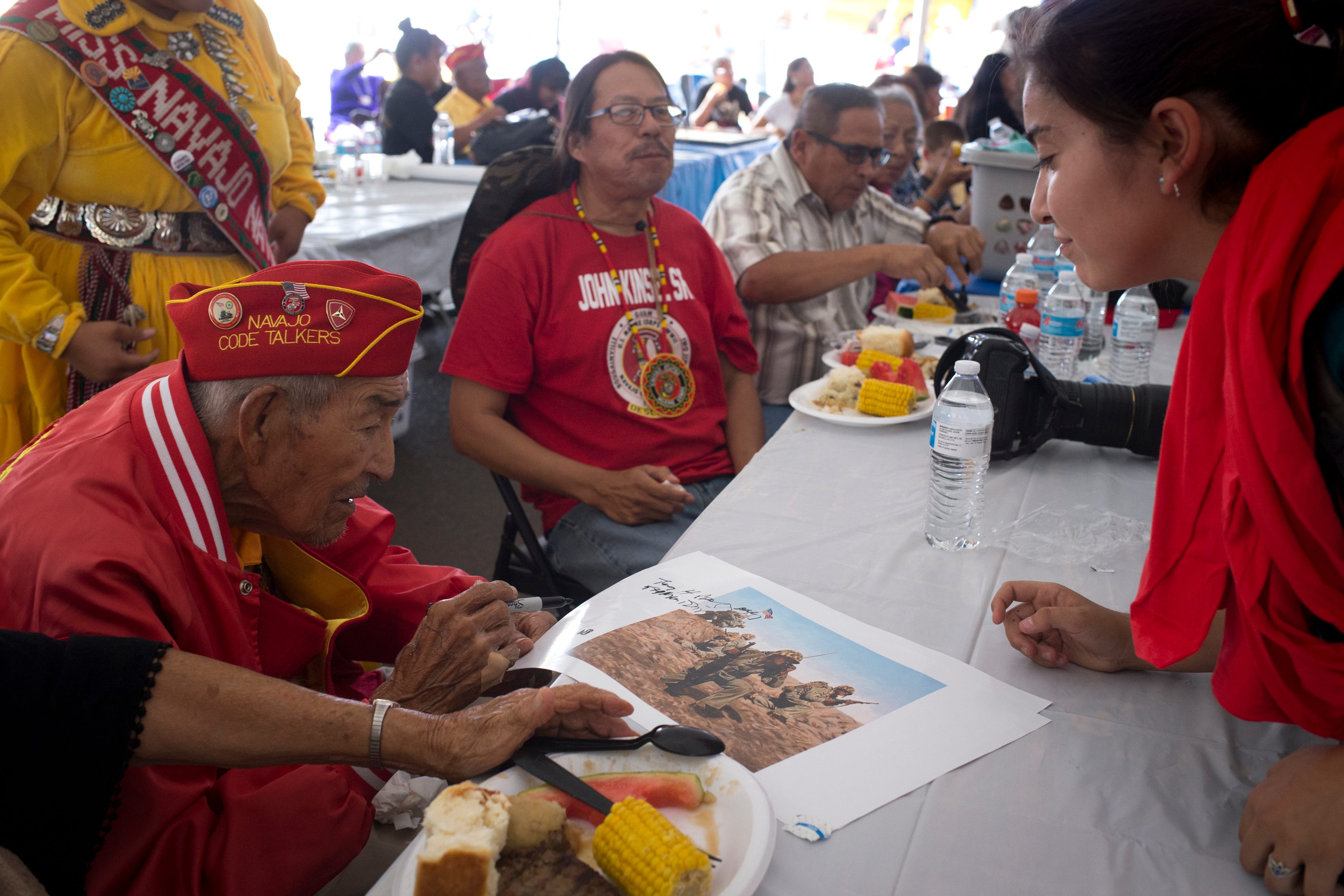 Navajo Code Talker Alfred Newman signs a poster after the Navajo Nation Code Talkers Day ceremony Aug. 14, 2018, at the Veterans Memorial Park in Window Rock.