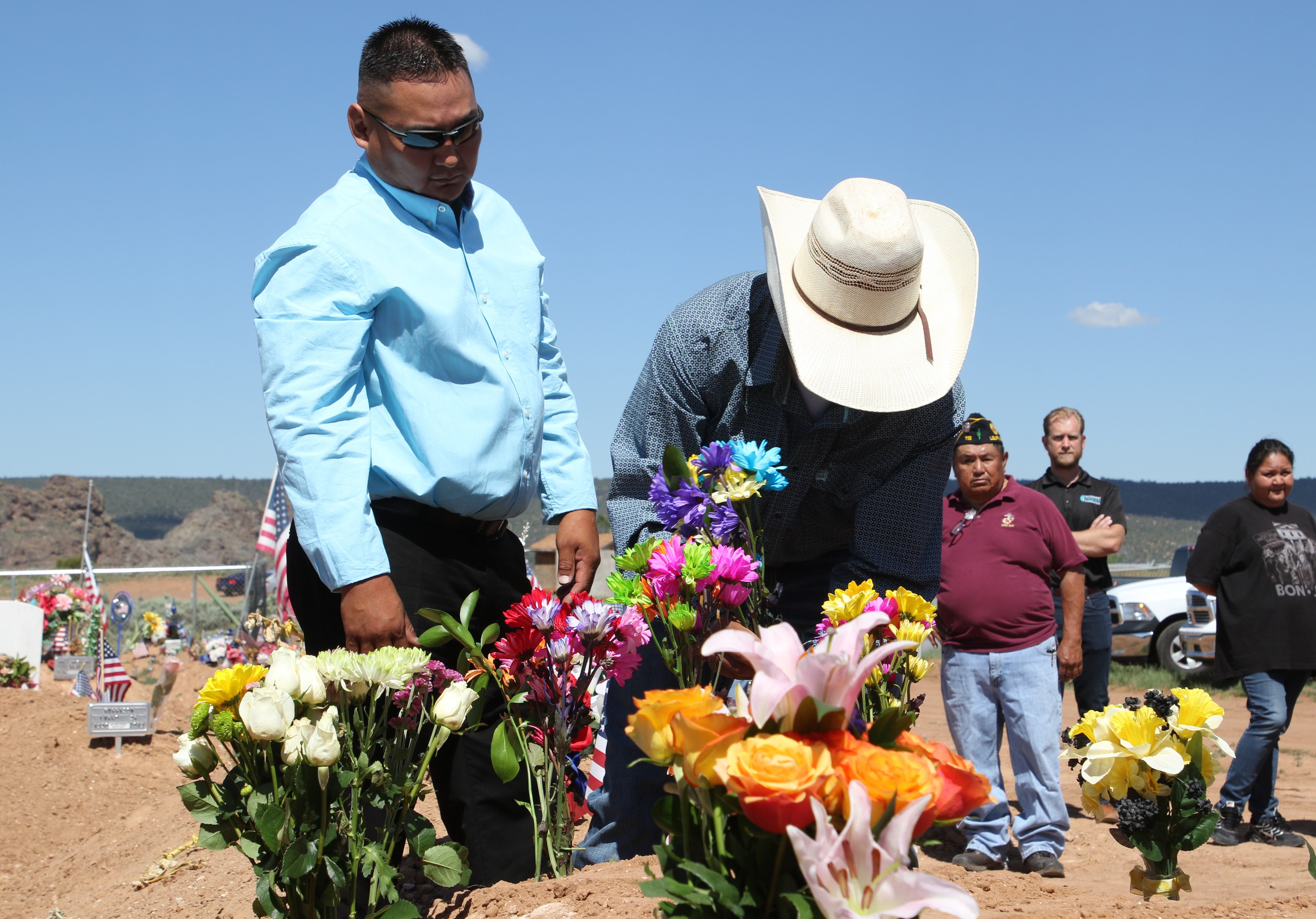 Dewhite Brown, left, watches as flowers are placed on the grave of his father, Navajo Code Talker William Tully Brown Sr., on June 6 at the Fort Defiance Veterans Cemetery in Fort Defiance, Ariz.