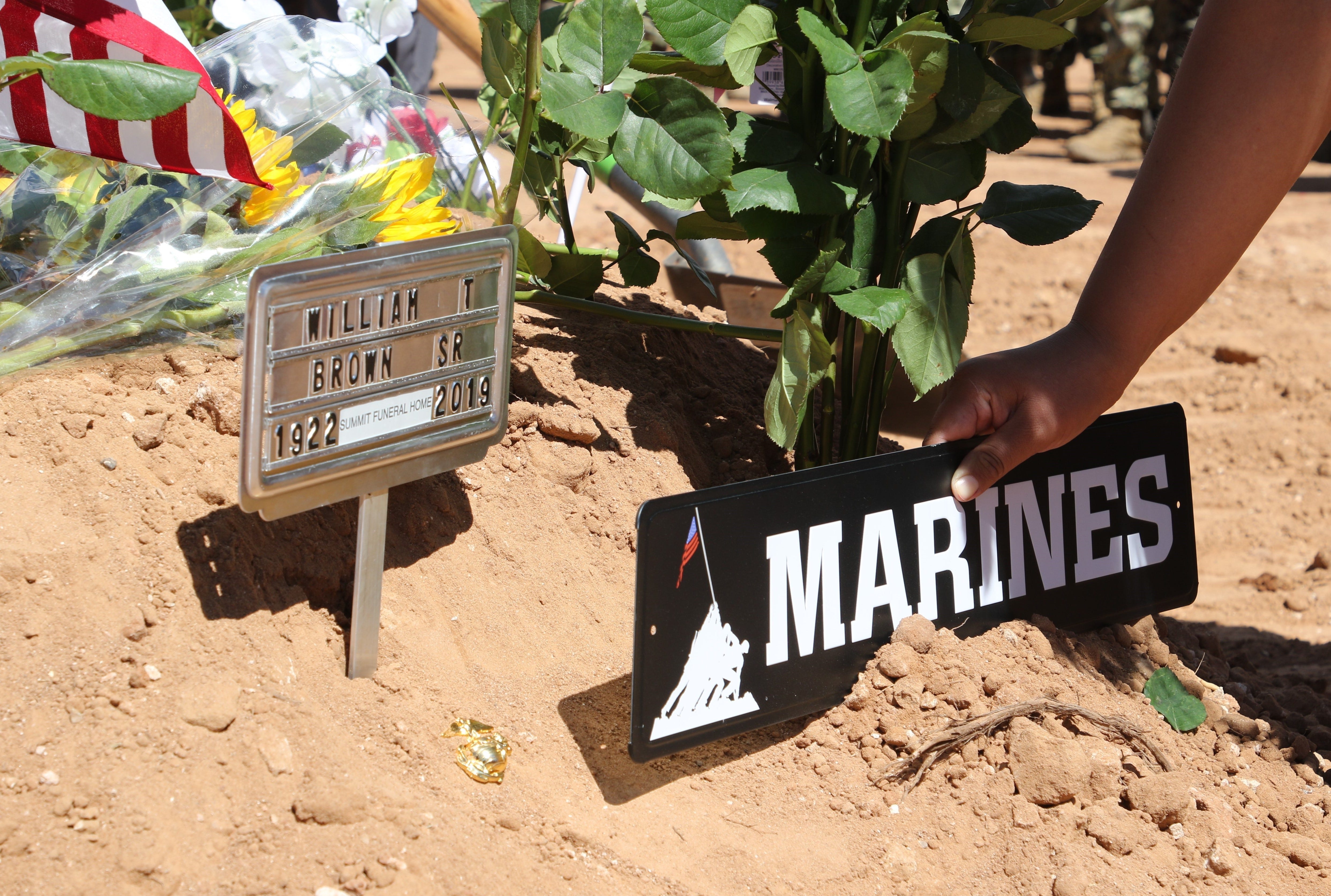 A relative places signage on the grave for Navajo Code Talker William Tully Brown Sr. on June 6 at the Fort Defiance Veterans Cemetery in Fort Defiance, Ariz.