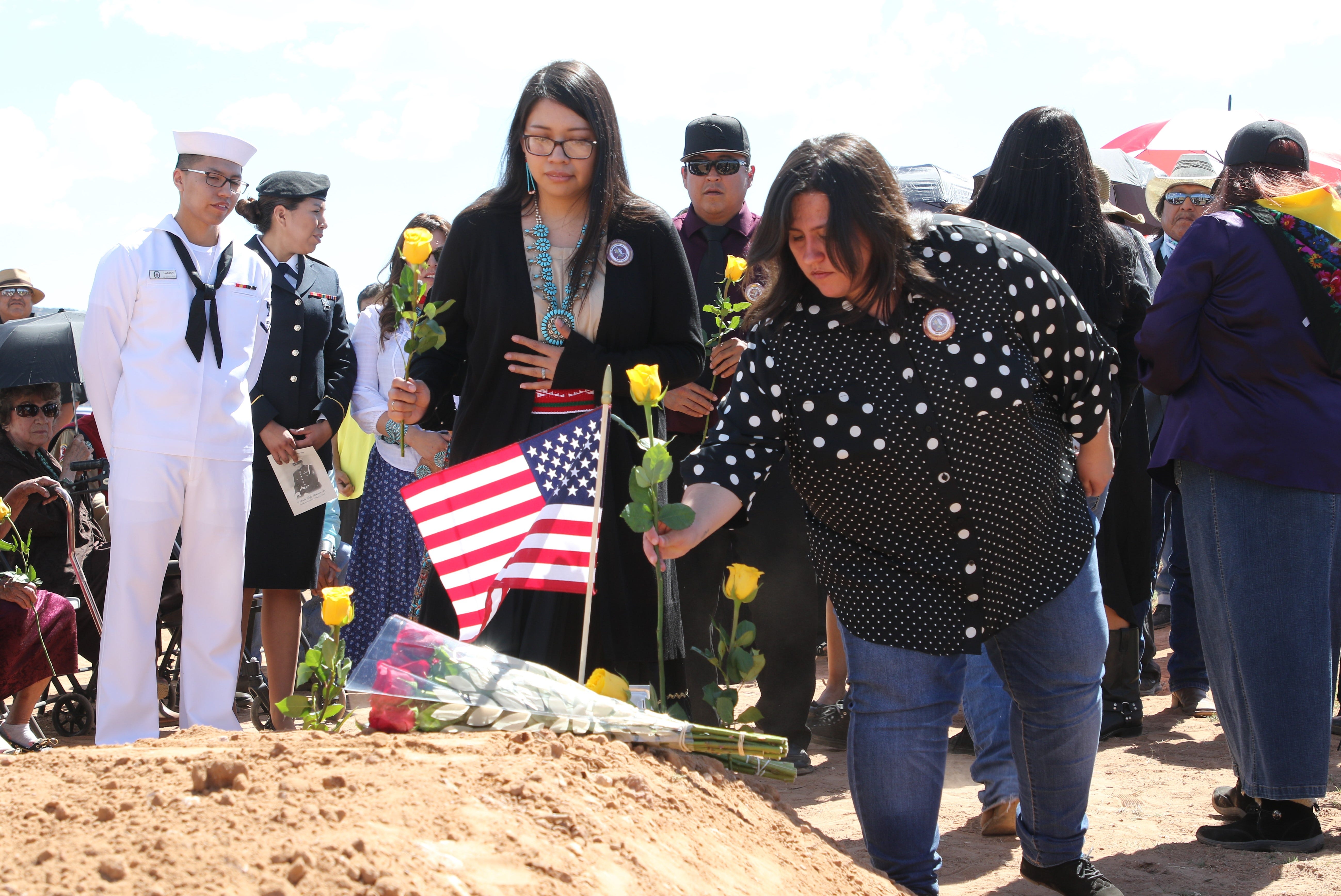 Relatives of Navajo Code Talker William Tully Brown Sr. place flowers his grave at the Fort Defiance Veterans Cemetery on June 6 in Fort Defiance, Ariz.