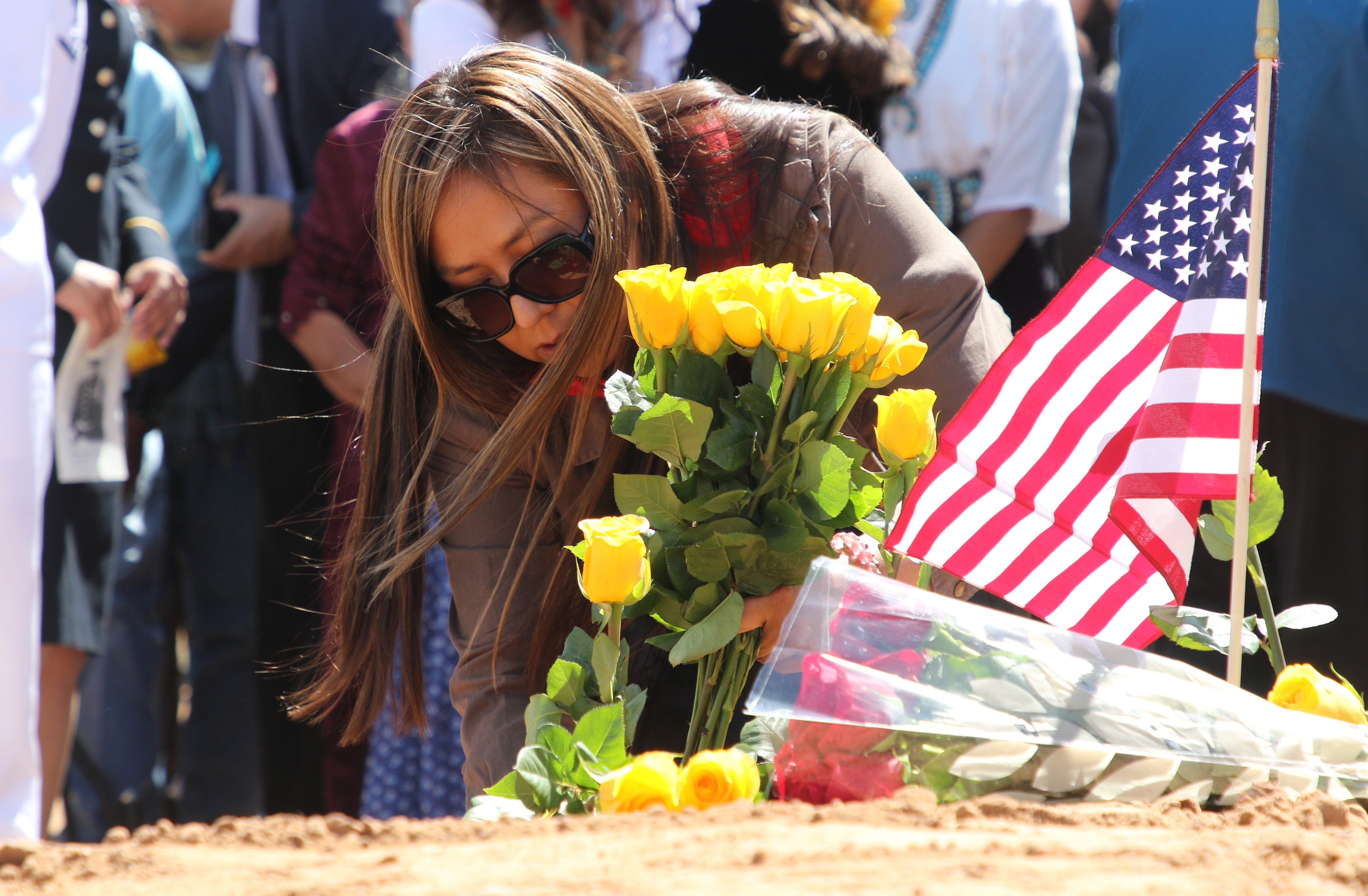 Delilah Yazzie places roses on the grave of her grandfather, Navajo Code Talker William Tully Brown Sr., on June 6 at the Fort Defiance Veterans Cemetery in Fort Defiance, Ariz.