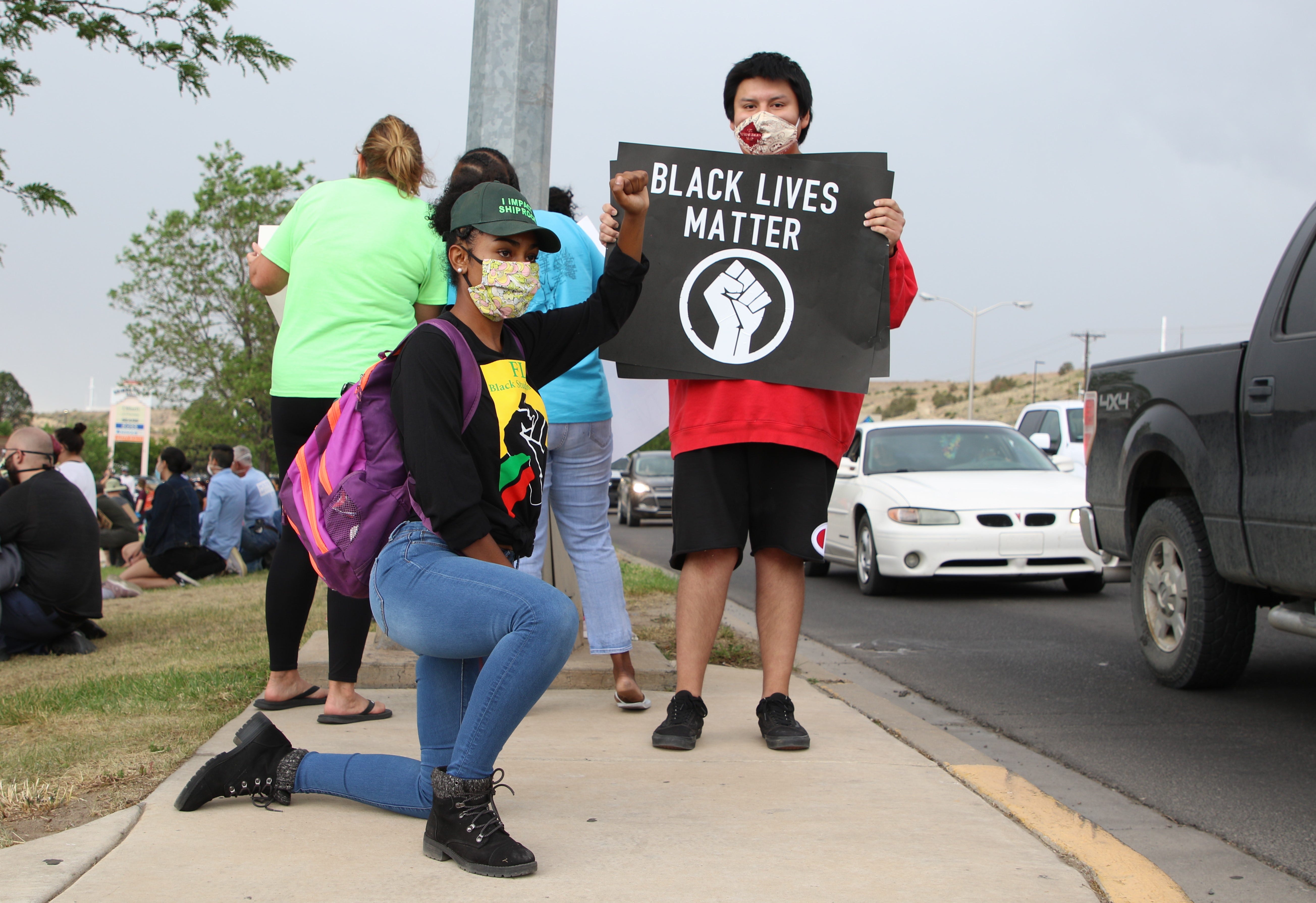 Rhakel Lewis Adams, left, takes a knee in solidarity while Zubick Taliman holds a sign in protest on June 1 near Animas Valley Mall in Farmington that called for justice in George Floyd's death in Minneapolis.