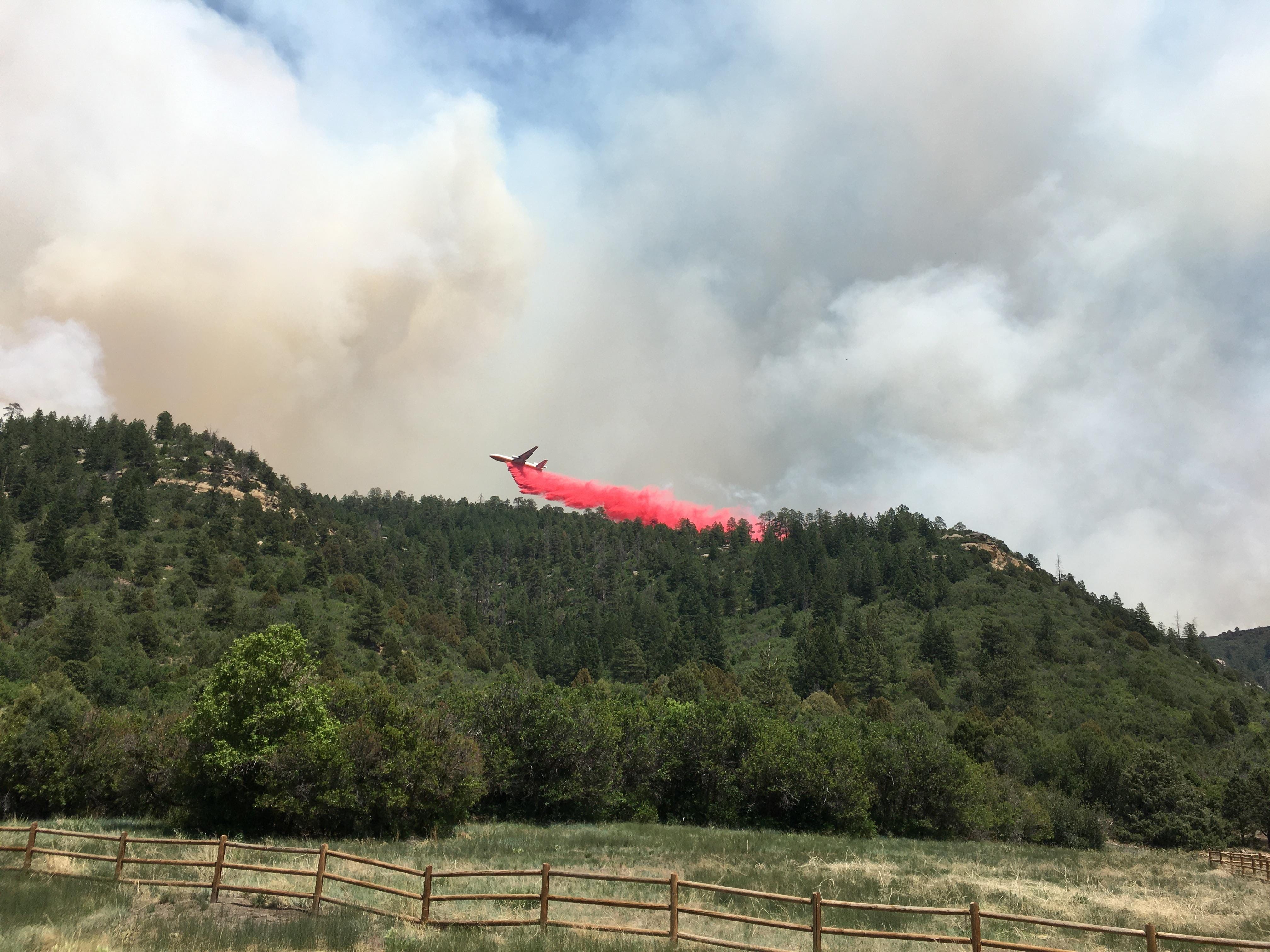 A plane drops retardant on the East Canyon Fire, Monday, June 15, 2020, in Colorado.