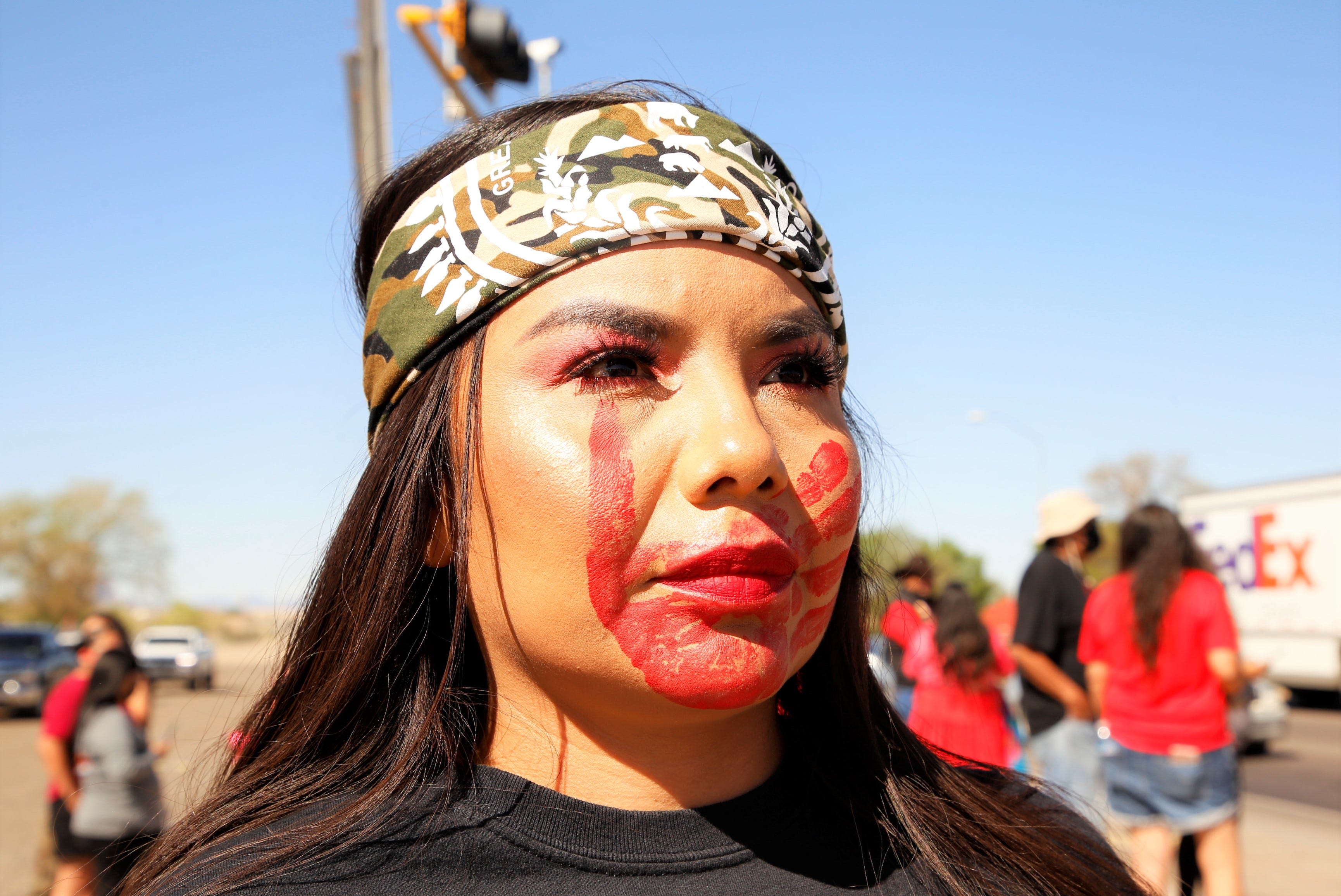 A red handprint indicating solidarity with Missing and Murdered Indigenous Women is shown on Christelle Tsosie's face during the MMIW Memorial Honor Walk on May 5 in Shiprock.